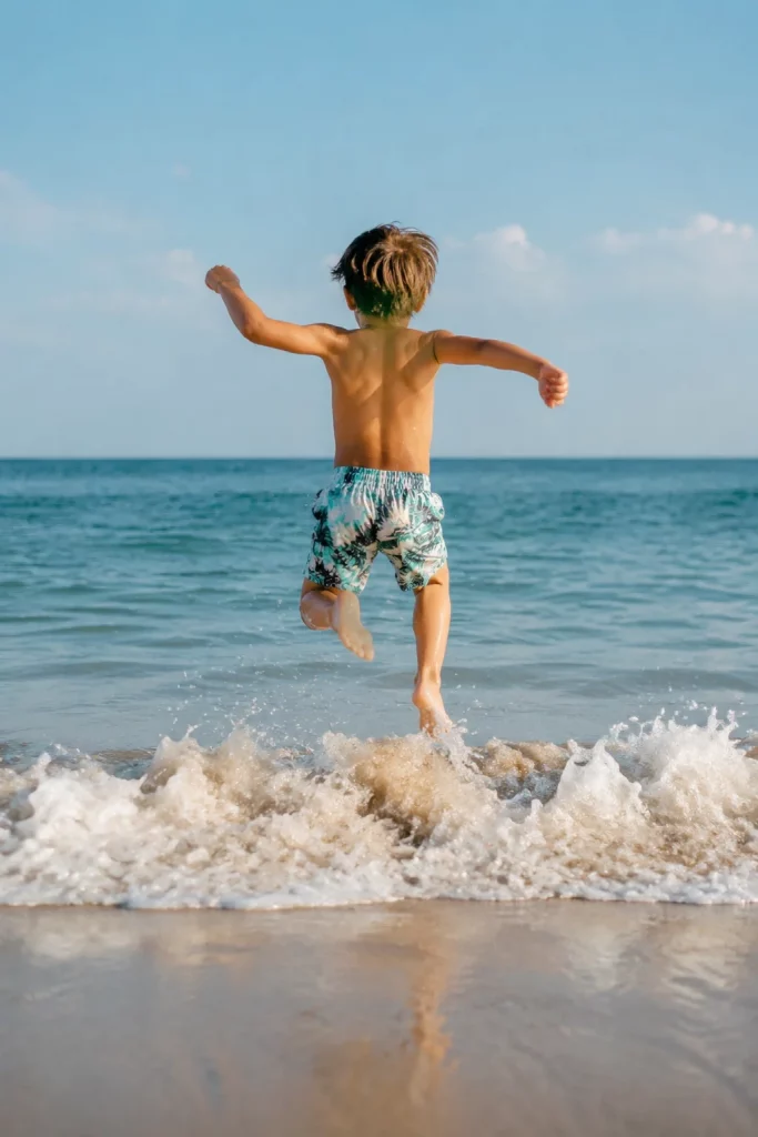 Niño saltando olas en la playa como ejercicio de desarrollo motor en verano