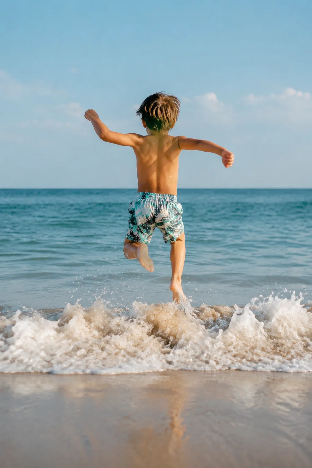 Niño saltando olas en la playa como ejercicio de desarrollo motor en verano